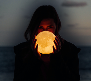 Girl holding glowing orb to represent the moon
