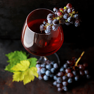 glass of red wine with grapes