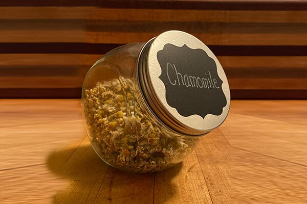 a glass jar holding dried chamomile flowers