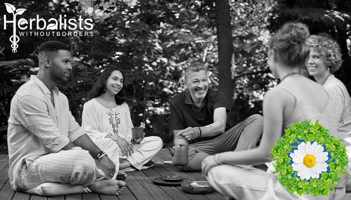 Group of people sitting in a circle outside, sharing a cup of tea.